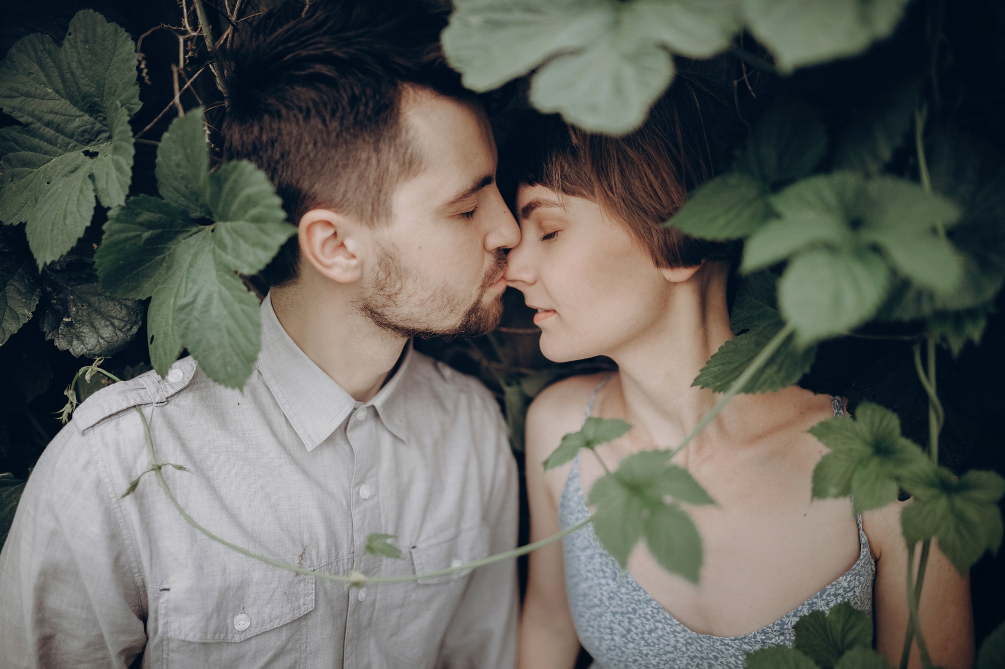 stylish-hipster-couple-kissing-in-green-leaves-holding-hands.jpg